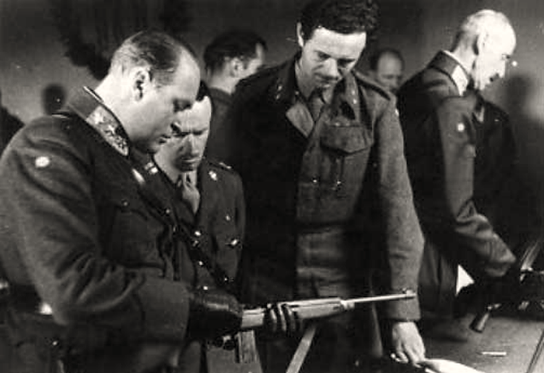 Kong Haakon (t.h.) og kronprins Olav (t.v.) besøkte flere ganger de norske soldatene som var under trening i England og Skottland. Jens-Anton Poulsson står midt i bildet. (Foto: Norsk Hjemmefrontmuseum).